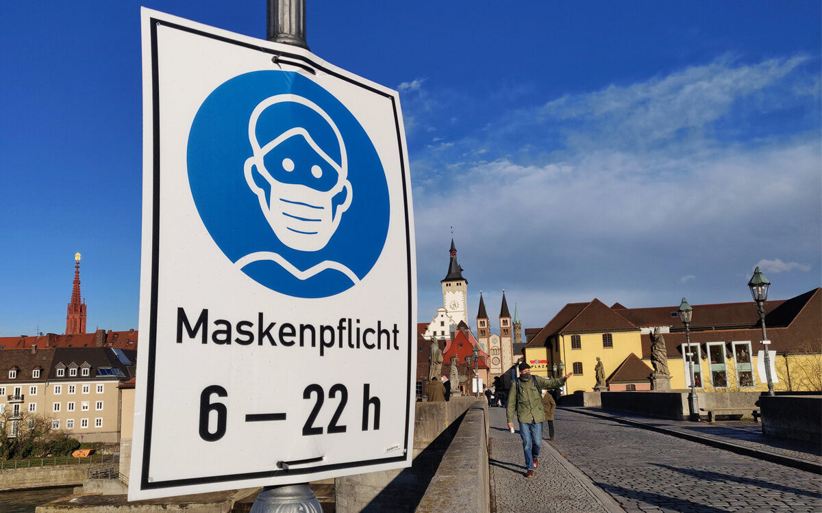 Maskenpflicht steht auf einem Schild auf Alte Mainbrücke in Würzburg auf der linken Seite Maskenpflicht steht auf einem Schild auf Alte Mainbrücke in Würzburg auf der linken Seite